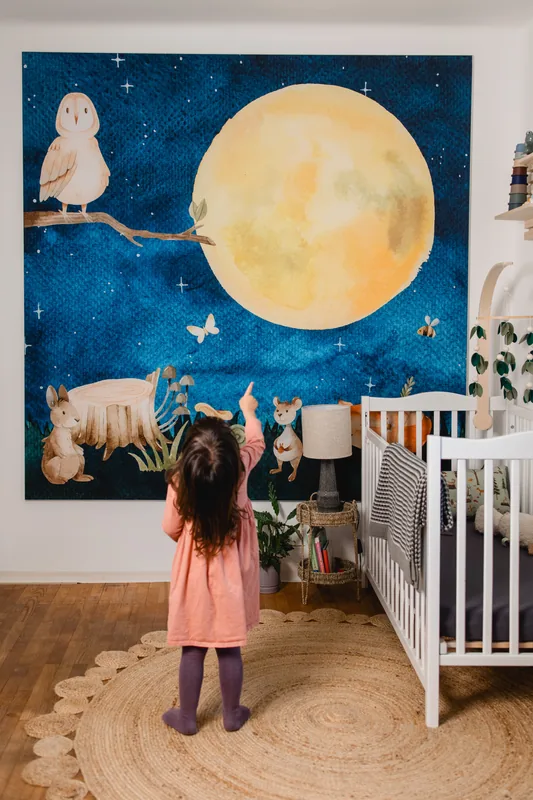 Kinderzimmer mit textiler Wandfläche, Eule und Mond über dem Gitterbett